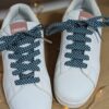 Lacets en tissu vert à pois sur baskets blanches, un choix fantaisie pour personnaliser vos chaussures et apporter de la couleur à votre look.