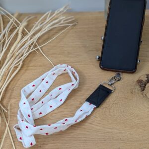 Lanière de téléphone avec imprimé cœurs rouges en tissu, accessoire original pour un look unique.