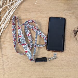 Lanière de téléphone avec imprimé fleuri rouge en tissu, accessoire original pour un look unique.